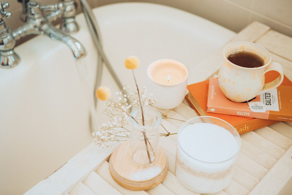 Relaxing bath set up with candles, flowers, books and a cup of tea 