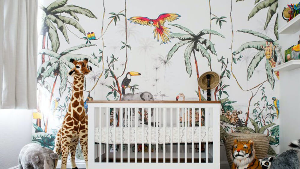 Nursery decorated with jungle wallpaper and stuffed toys of jungle animals